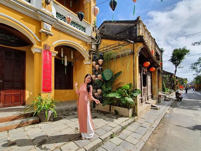 Frau in traditioneller Kleidung posiert auf einer Straße in Hoi An, Vietnam.