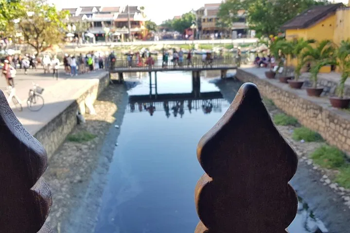 Blick entlang eines Kanals mit einer Brücke und Menschen im Hintergrund.