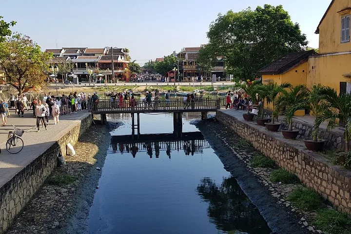 Canal with a bridge in a bustling town, likely Hoi An.