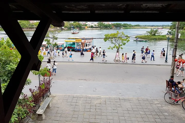View of a river with boats and people walking along the promenade.